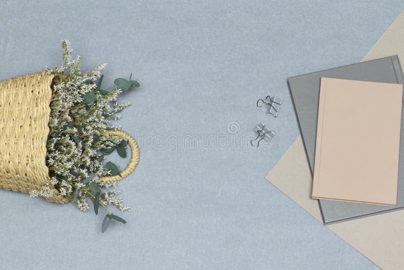 Het grijze notitieboekje & de paperclippen, de roze nota & het document, de stromand met witte bloemen en de eucalyptus vertakken stock foto Het grijze notitieboekje & de paperclippen, de roze nota & het document, de stromand met witte bloemen en de eucalyptus vertakken stock foto
