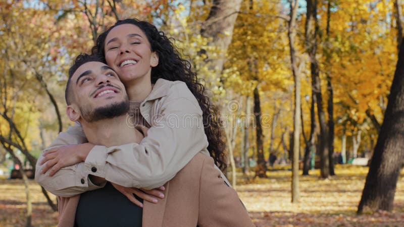 In het herfstpark zijn vrolijk hispanisch koppel op date in het herfstpark die glimlachte partners die genieten van een zonnige da