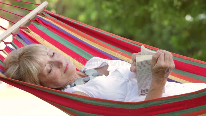 Het hogere Vrouw Ontspannen in Hangmat met Boek