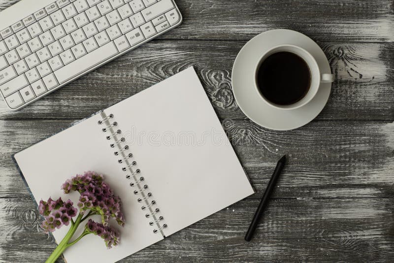 Het hoogste toetsenbord van de meningscomputer, lege notitieboekje en kop koffie en roze bloemen op grijze houten lijst stock afbeeldingen Het hoogste toetsenbord van de meningscomputer, lege notitieboekje en kop koffie en roze bloemen op grijze houten lijst stock afbeeldingen