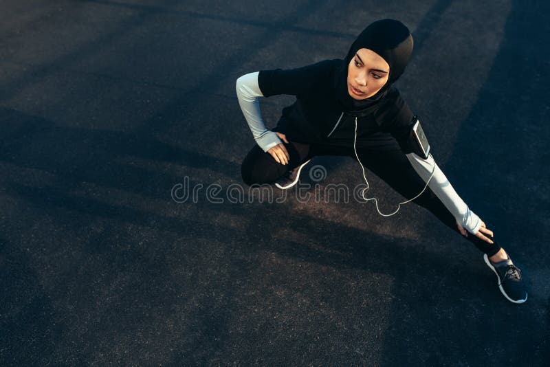 Islamic woman stretching after workout outdoors in the street. Muslim woman in sportswear exercising in morning. Islamic woman stretching after workout outdoors in the street. Muslim woman in sportswear exercising in morning