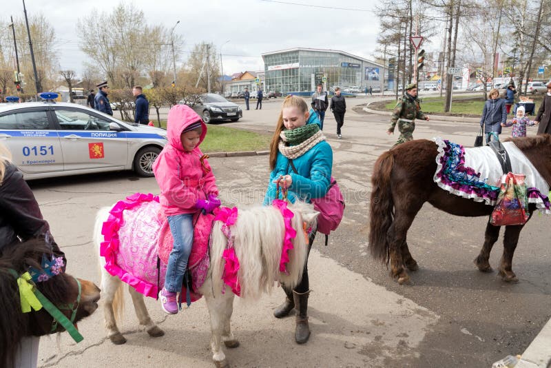 Het Ittlemeisje zit op een poney, bevindt een meisje zich naast haar, tegen de achtergrond van een politiewagen stock afbeelding Het Ittlemeisje zit op een poney, bevindt een meisje zich naast haar, tegen de achtergrond van een politiewagen stock afbeelding
