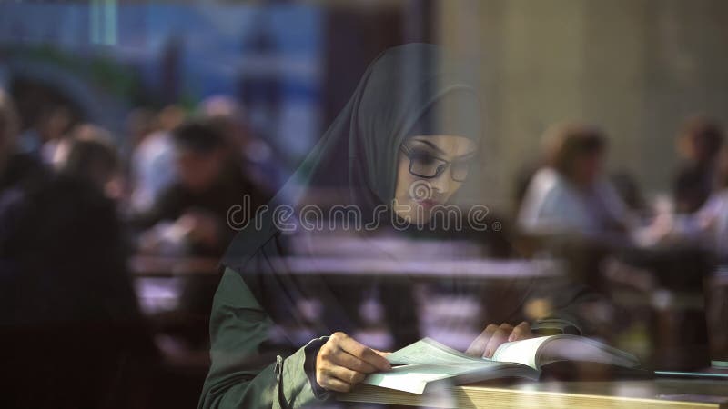 Het jonge Arabische boek van de damelezing in koffie, student die voor examens, literatuur voorbereidingen treffen stock afbeelding Het jonge Arabische boek van de damelezing in koffie, student die voor examens, literatuur voorbereidingen treffen stock afbeelding