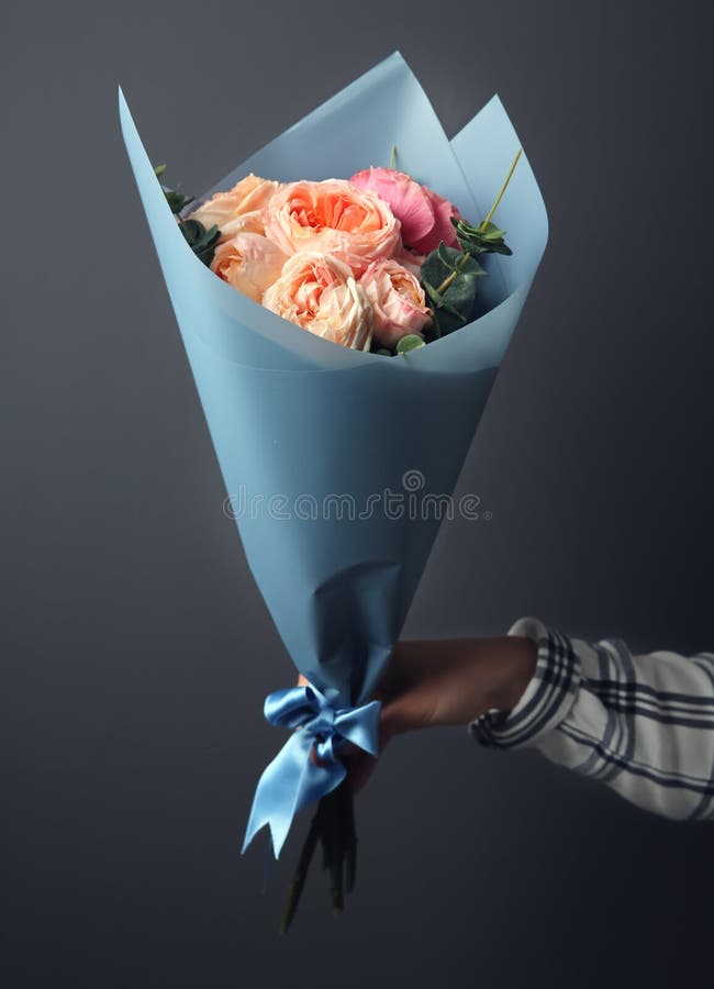 Het jonge boeket van de vrouwenholding van mooie bloemen op grijze achtergrond royalty-vrije stock fotografie Het jonge boeket van de vrouwenholding van mooie bloemen op grijze achtergrond royalty-vrije stock fotografie