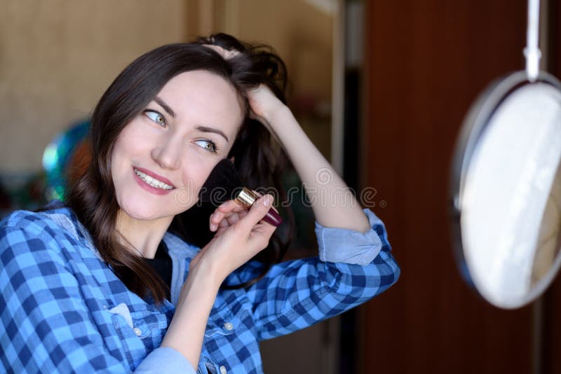 Het jonge brunette verbetert samenstelling bij de ronde spiegel in de slaapkamer stock afbeelding Het jonge brunette verbetert samenstelling bij de ronde spiegel in de slaapkamer stock afbeelding