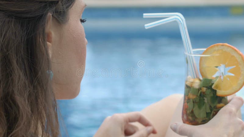 Het jonge dame ontspannen door pool nippende cocktail en het genieten van de van reis van de de zomervakantie