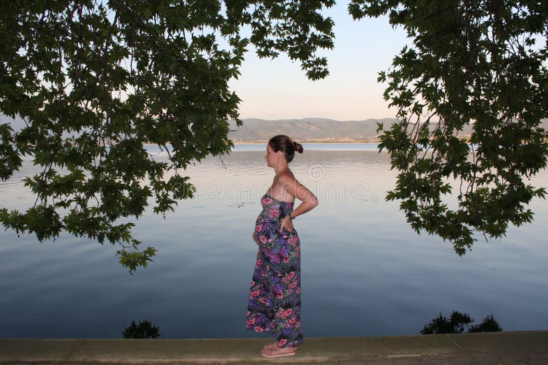Het jonge en zwangere vrouw ontspannen naast het meer royalty-vrije stock foto's Het jonge en zwangere vrouw ontspannen naast het meer royalty-vrije stock foto's