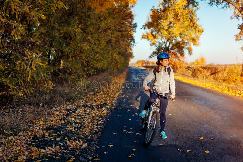 Het jonge fietser berijden op de herfstgebied bij zonsondergang Het gelukkige vrouw glimlachen stock foto Het jonge fietser berijden op de herfstgebied bij zonsondergang Het gelukkige vrouw glimlachen stock foto