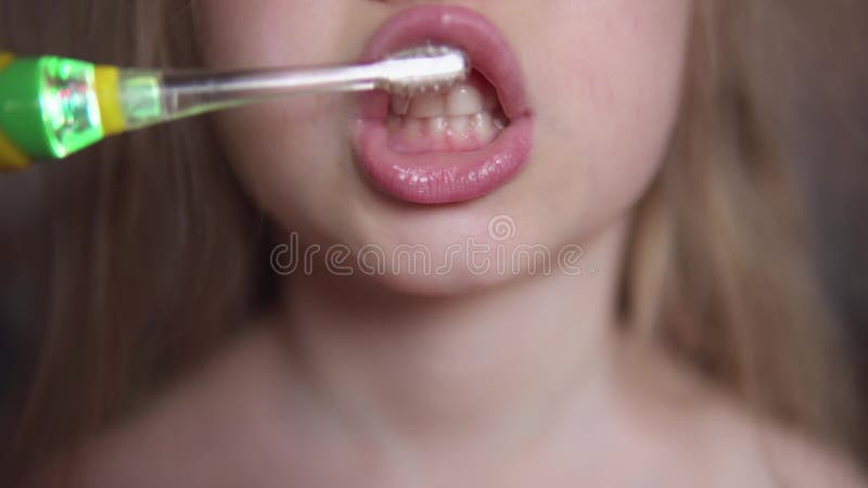 Het jonge geitje borstelt zijn tanden met een elektrische tandenborstel