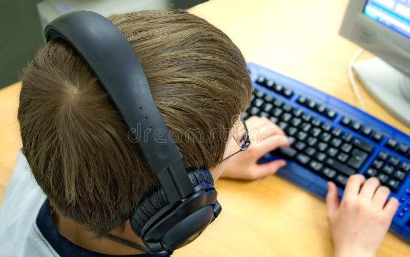 Young boy with headphones working with a computer. Young boy with headphones working with a computer.