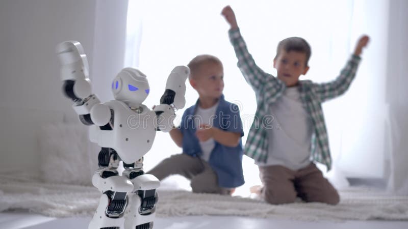 Het jonge geitjesspel met robot thuis, modern wit stuk speelgoed neemt sport in dienst en toont bewegingen voor jongens