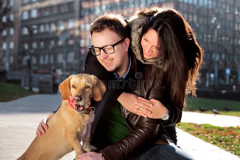 Het jonge gelukkige paar met hond geniet van in een mooie dag stock afbeelding Het jonge gelukkige paar met hond geniet van in een mooie dag stock afbeelding