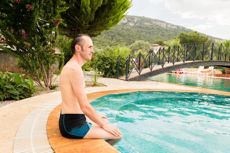 Het jonge Kaukasische mens ontspannen dichtbij zwembad in een toevlucht stock afbeelding Het jonge Kaukasische mens ontspannen dichtbij zwembad in een toevlucht stock afbeelding