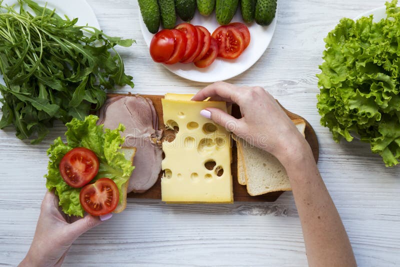 Het jonge meisje bereidt een sandwich in de keuken voor stock afbeelding Het jonge meisje bereidt een sandwich in de keuken voor stock afbeelding