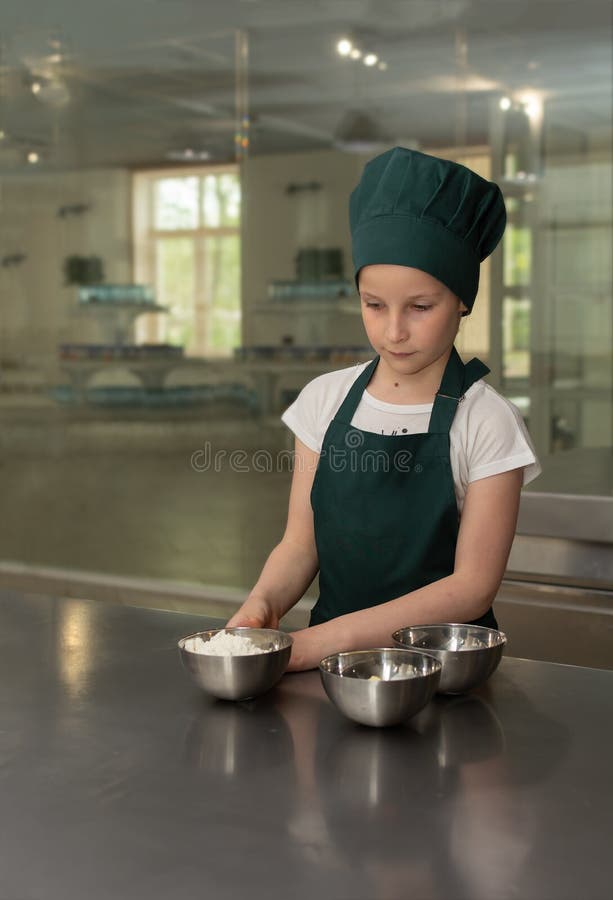 Het jonge meisje van de kokchef-kok in groene chef-kok GLB mengt de ingredi?nten voor de cake royalty-vrije stock foto's Het jonge meisje van de kokchef-kok in groene chef-kok GLB mengt de ingredi?nten voor de cake royalty-vrije stock foto's