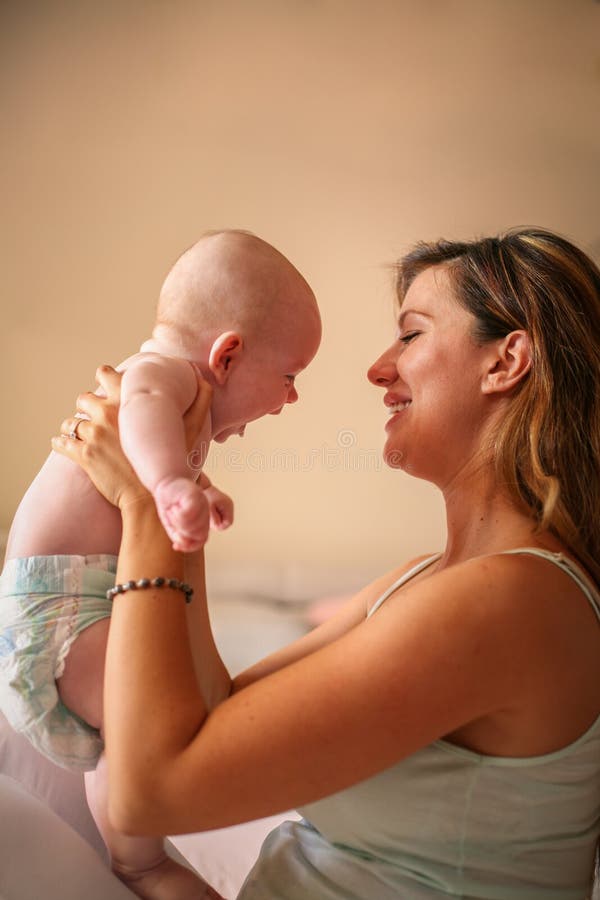 Het jonge moeder spelen met haar babyjongen in bed royalty-vrije stock afbeelding Het jonge moeder spelen met haar babyjongen in bed royalty-vrije stock afbeelding