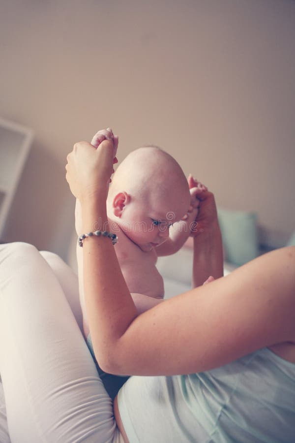 Het jonge moeder spelen met haar babyjongen in bed stock afbeelding Het jonge moeder spelen met haar babyjongen in bed stock afbeelding