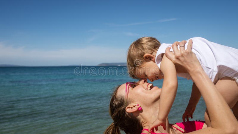 Het jonge moeder spelen met haar dochter door het overzees stock foto Het jonge moeder spelen met haar dochter door het overzees stock foto