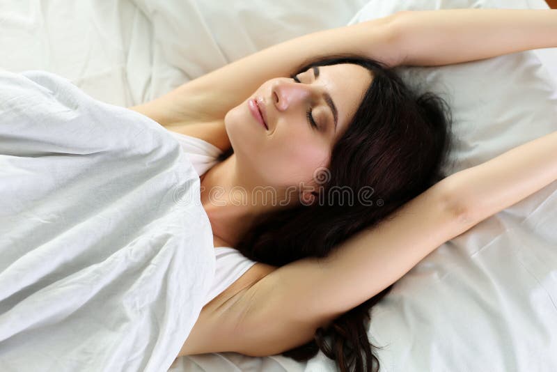 Het jonge mooie glimlachen en donkerbruine vrouw die in bed liggen royalty-vrije stock foto's Het jonge mooie glimlachen en donkerbruine vrouw die in bed liggen royalty-vrije stock foto's