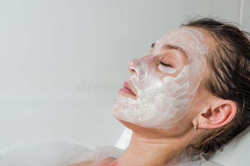 Young beautiful girl makes a white face mask for beauty during spa treatments in the bathroom. Young beautiful girl makes a white face mask for beauty during spa treatments in the bathroom.