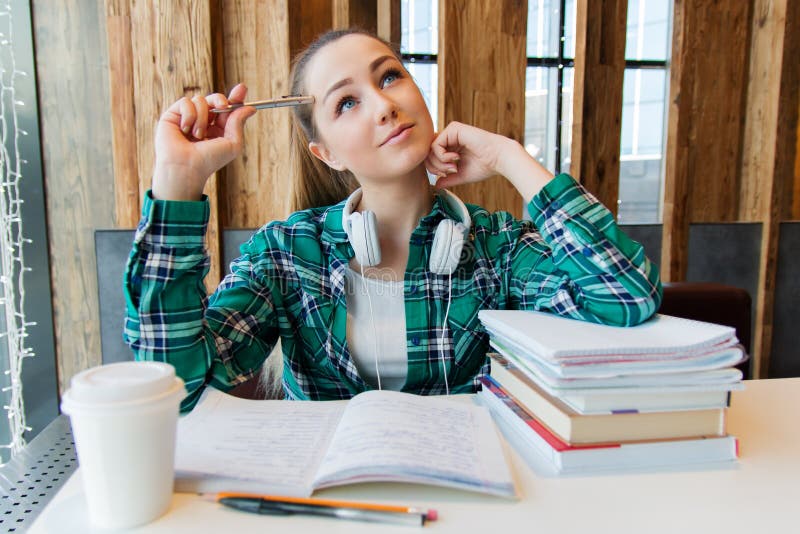 Het jonge mooie studentenmeisje doet haar thuiswerk of treft aan de examens voorbereidingen die met boekenvoorbeeldenboeken situe royalty-vrije stock afbeeldingen Het jonge mooie studentenmeisje doet haar thuiswerk of treft aan de examens voorbereidingen die met boekenvoorbeeldenboeken situe royalty-vrije stock afbeeldingen