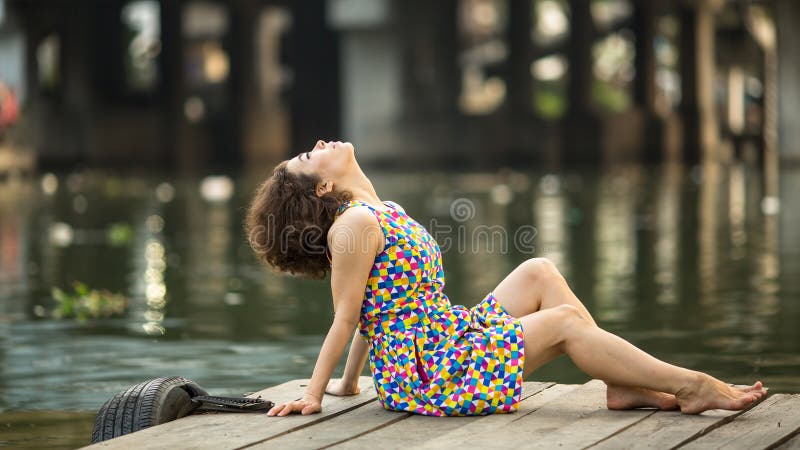 Het jonge mooie vrouw stellen op een houten rivierpijler
