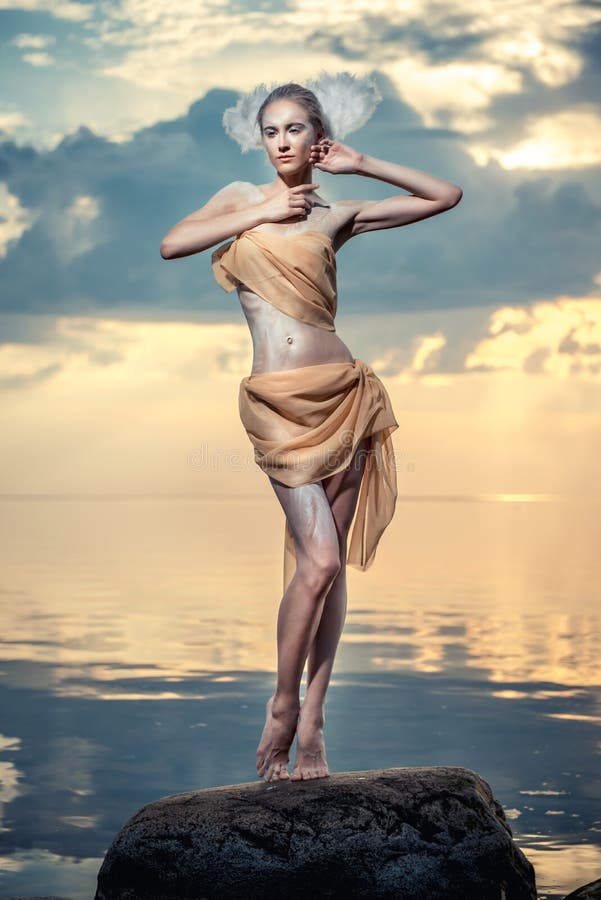 Het jonge mooie vrouw stellen op het strand bij zonsondergang royalty-vrije stock afbeeldingen Het jonge mooie vrouw stellen op het strand bij zonsondergang royalty-vrije stock afbeeldingen