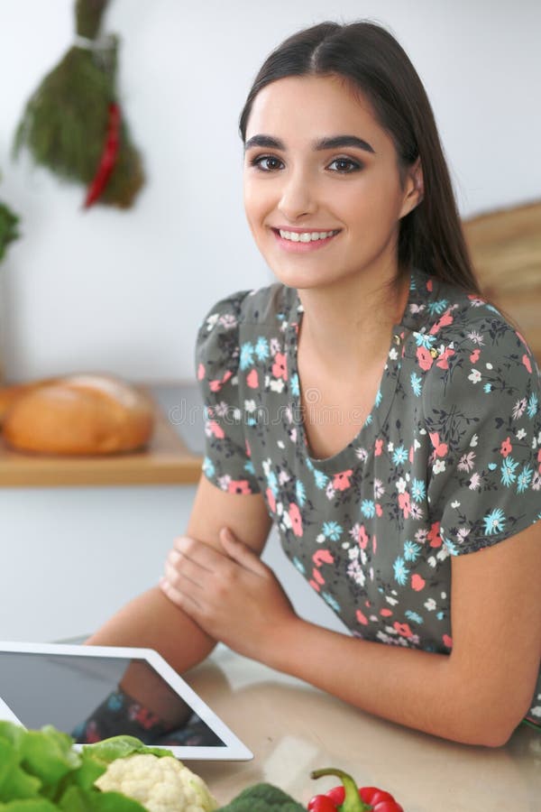 Het jonge Spaanse vrouw of studenten koken in keuken Meisje die tablet gebruiken om online het winkelen te maken of een nieuw rec stock foto Het jonge Spaanse vrouw of studenten koken in keuken Meisje die tablet gebruiken om online het winkelen te maken of een nieuw rec stock foto