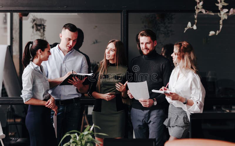 Het jonge team van collega's werkt met documenten en bespreekt het project in een modieus modern bureau Het werkproces in stock foto's Het jonge team van collega's werkt met documenten en bespreekt het project in een modieus modern bureau Het werkproces in stock foto's