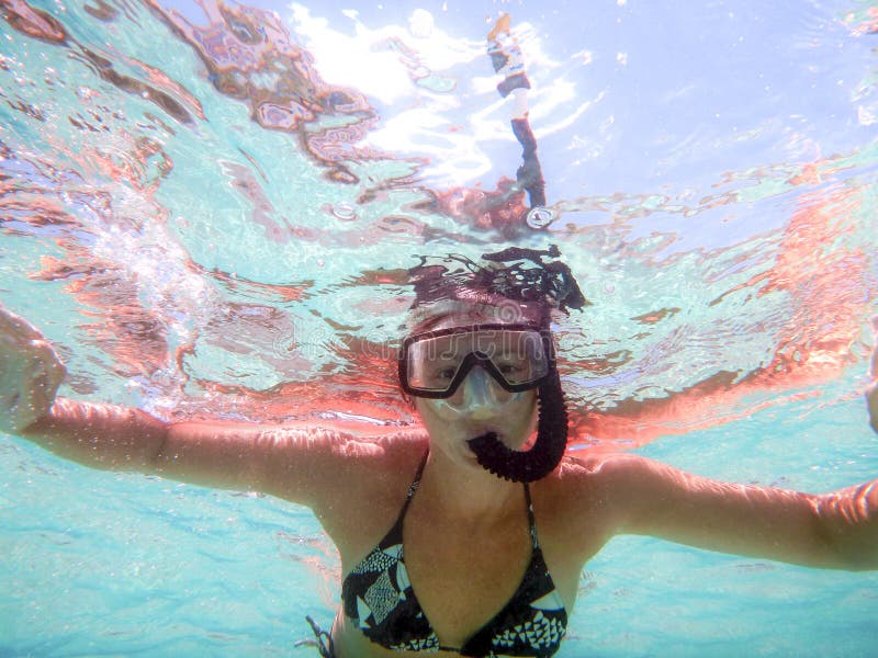Het jonge vrouw schieten in water van onderaan met open wapens met masker en snorkelt in een mooi spel van gekleurde waterbezinni stock afbeelding Het jonge vrouw schieten in water van onderaan met open wapens met masker en snorkelt in een mooi spel van gekleurde waterbezinni stock afbeelding