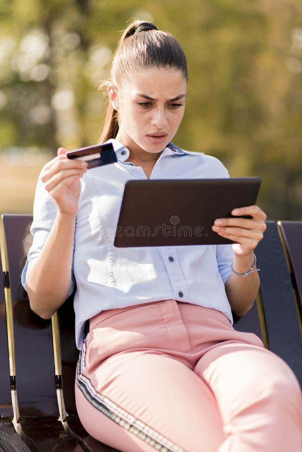 Het jonge vrouw winkelen online met creditcard in het park royalty-vrije stock afbeelding Het jonge vrouw winkelen online met creditcard in het park royalty-vrije stock afbeelding