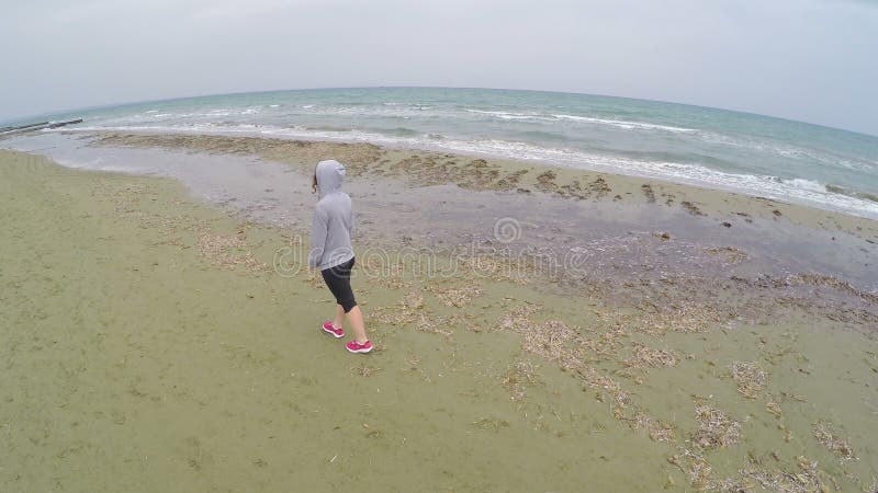 Het jonge vrouwelijke lopen op het strand en het denken over het leven, luchthommelschot