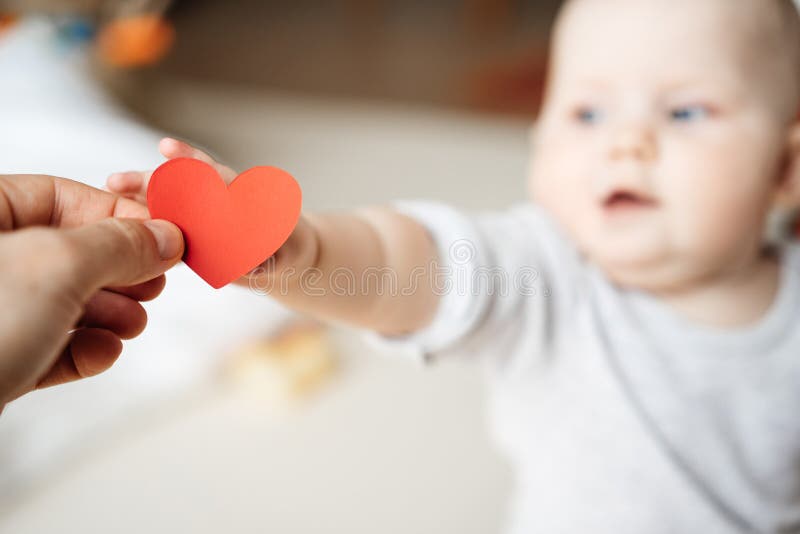 Het kind rekt en neemt het symbool van een rood hart in de hand uit stock foto Het kind rekt en neemt het symbool van een rood hart in de hand uit stock foto