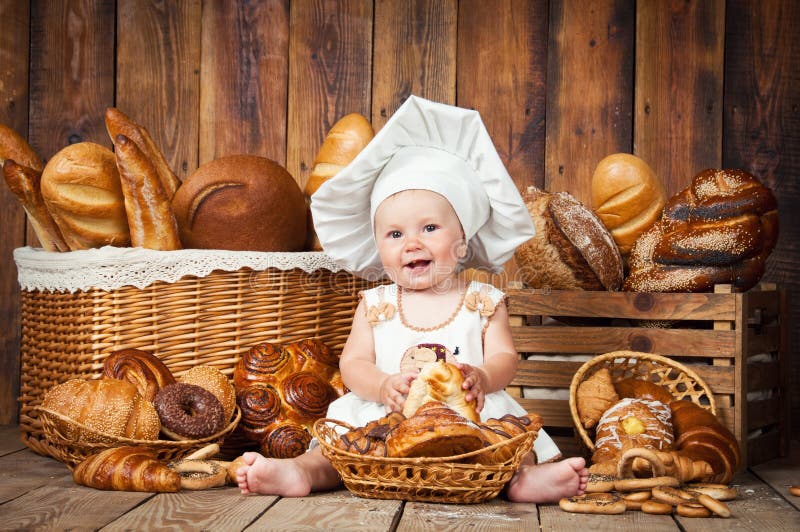 Het kleine kind kookt een croissant op de achtergrond van manden met broodjes en brood stock afbeelding Het kleine kind kookt een croissant op de achtergrond van manden met broodjes en brood stock afbeelding