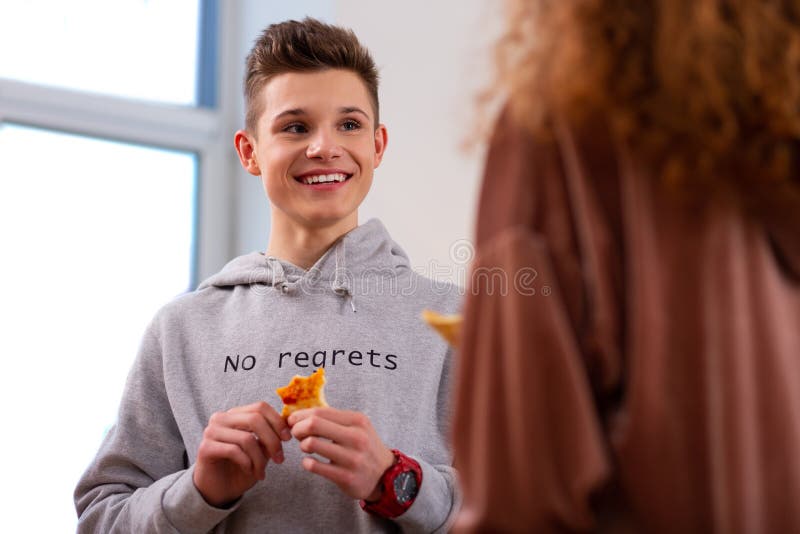 Het knappe stuk van de tienerholding van pizza terwijl het eten met krullend meisje stock foto's Het knappe stuk van de tienerholding van pizza terwijl het eten met krullend meisje stock foto's