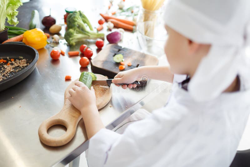 Het koken met groenten Weinig snijden de jongens` s handen verschillende ingrediënten voor een salade op een houten raad royalty-vrije stock foto's Het koken met groenten Weinig snijden de jongens` s handen verschillende ingrediënten voor een salade op een houten raad royalty-vrije stock foto's
