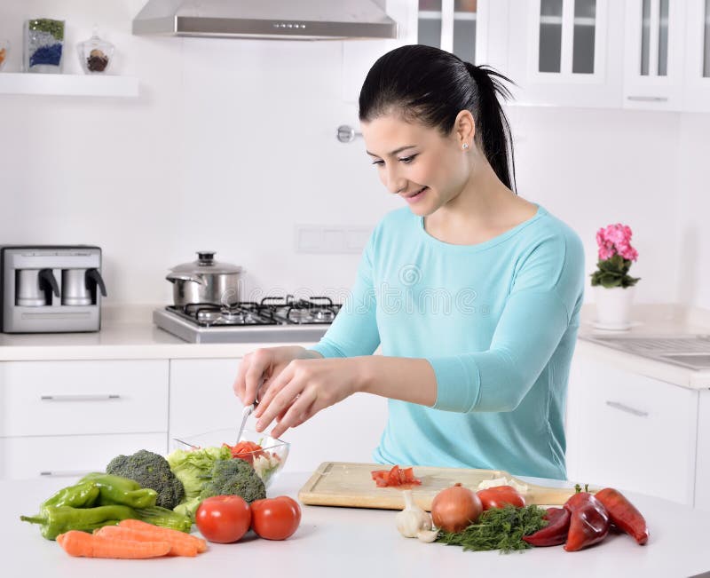 Het koken van de vrouw in nieuwe keuken die gezond voedsel met groenten maakt