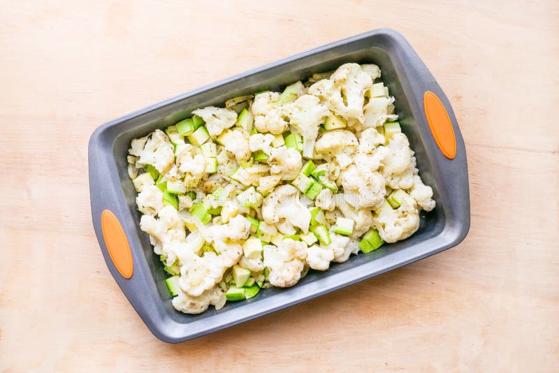 Het koken van plantaardige braadpan van bloemkool en courgette binnen stock afbeelding Het koken van plantaardige braadpan van bloemkool en courgette binnen stock afbeelding