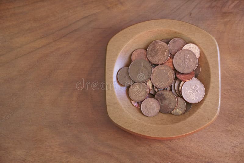 Het koperpence van inzamelingsmuntstukken besparingen in houten kom stock afbeeldingen Het koperpence van inzamelingsmuntstukken besparingen in houten kom stock afbeeldingen
