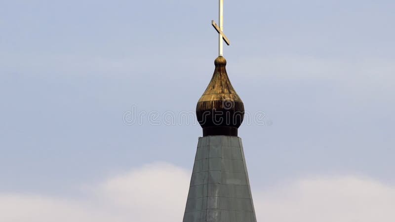 Het kruis boven aan een orthodoxe christelijke kerk tegen een kalme blauwe hemel