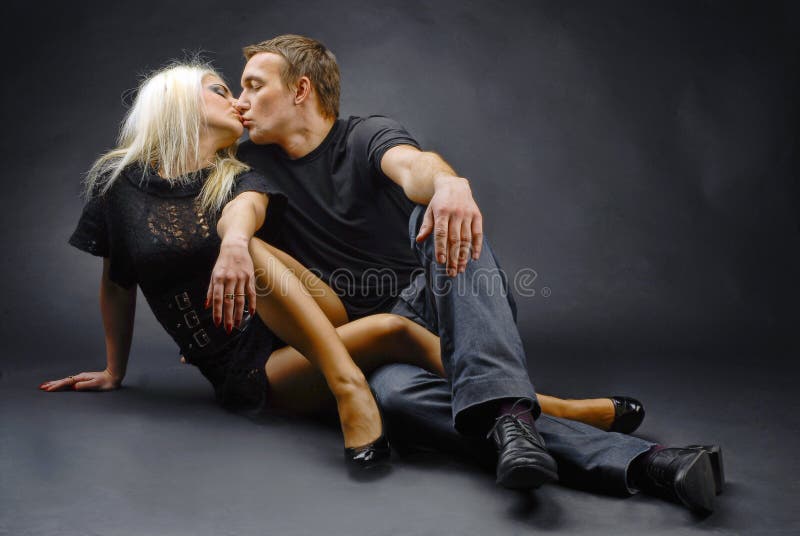 There are two models, male and female laid on the floor. They are kissing each other. There are two models, male and female laid on the floor. They are kissing each other