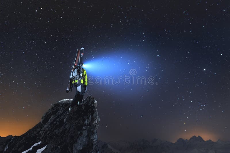 Het landschap van de nacht Een professionele backcountry skiër met een rugzak en skis bevindt zich op een rots in de bergen en gl royalty-vrije stock afbeeldingen Het landschap van de nacht Een professionele backcountry skiër met een rugzak en skis bevindt zich op een rots in de bergen en gl royalty-vrije stock afbeeldingen