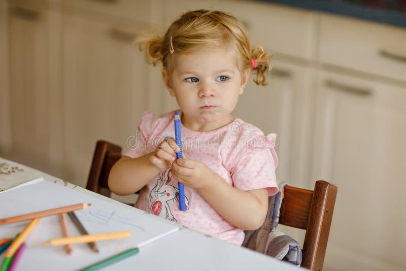 Het leuke aanbiddelijke babymeisje het leren schilderen met potloden Weinig tekening van het peuterkind thuis, gebruikend kleurri royalty-vrije stock foto Het leuke aanbiddelijke babymeisje het leren schilderen met potloden Weinig tekening van het peuterkind thuis, gebruikend kleurri royalty-vrije stock foto