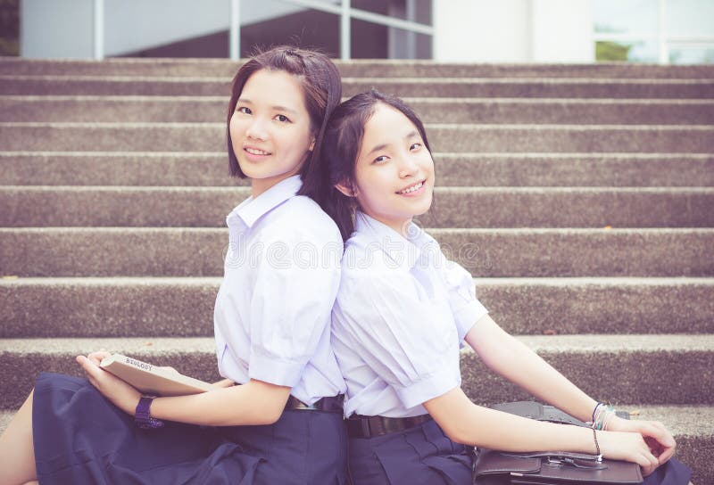 Het leuke Aziatische Thaise hoge het paar van de schoolmeisjesstudent leunen