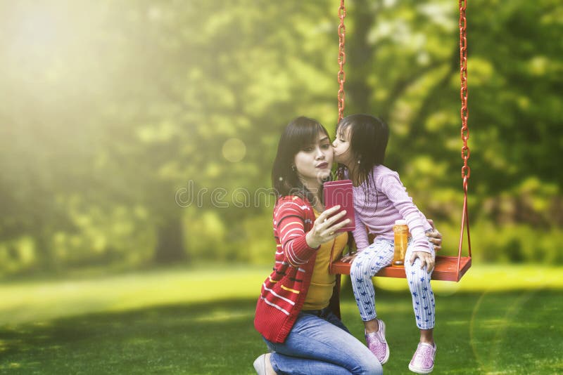 Het leuke kind kust haar moeder in het park royalty-vrije stock afbeelding Het leuke kind kust haar moeder in het park royalty-vrije stock afbeelding