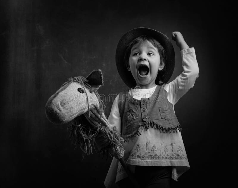 Het leuke meisje kleedde zich als een cowboy die met eigengemaakt h spelen royalty-vrije stock foto Het leuke meisje kleedde zich als een cowboy die met eigengemaakt h spelen royalty-vrije stock foto