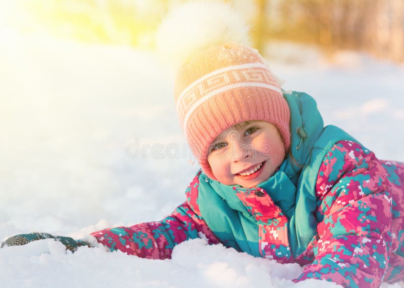 Het leuke meisje ligt op de sneeuw verlichte zon royalty-vrije stock foto Het leuke meisje ligt op de sneeuw verlichte zon royalty-vrije stock foto