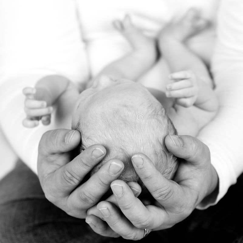 A powerful image of a father's hands hold his newborn child. A powerful image of a father's hands hold his newborn child.