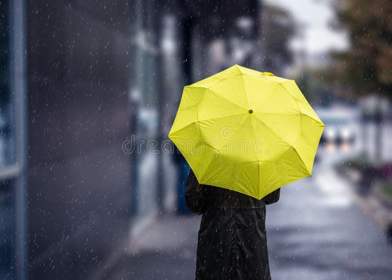 Het lopen op regenachtige dag met gele paraplu