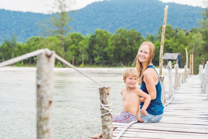 Het mamma en de zoon zitten op de oude pijler en genieten van het overzees stock afbeeldingen Het mamma en de zoon zitten op de oude pijler en genieten van het overzees stock afbeeldingen